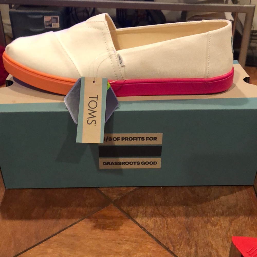 New Tom’s sneakers. Size 11 white with pink and orange accents on bottom.